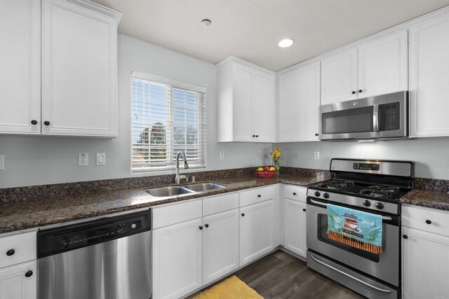 kitchen featuring stainless steel appliances, a sink, white cabinets, dark wood finished floors, and recessed lighting