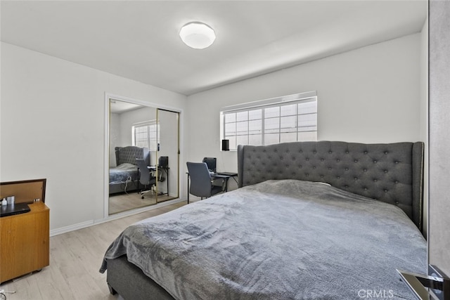 bedroom featuring baseboards, wood finished floors, and a closet