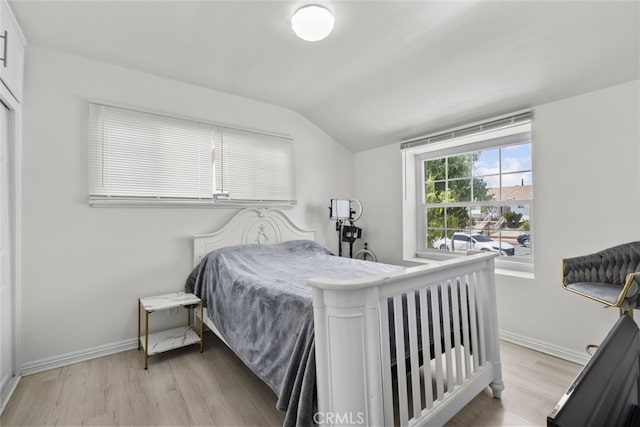 bedroom featuring baseboards, vaulted ceiling, and light wood finished floors
