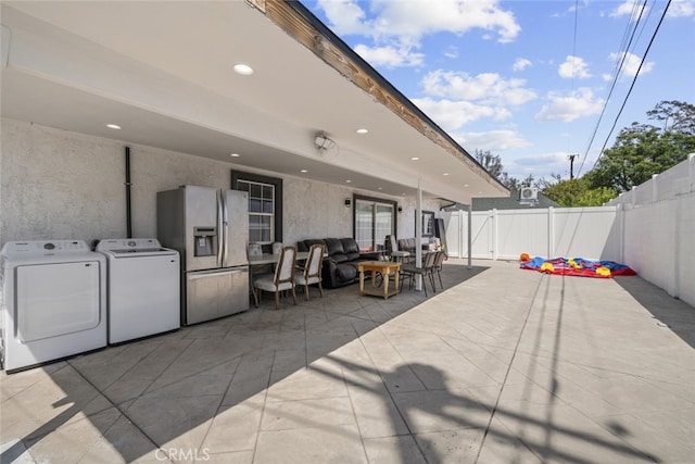 view of patio with a fenced backyard, outdoor dining area, and washer and dryer