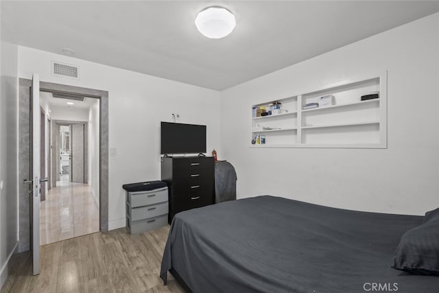 bedroom with baseboards, visible vents, and light wood finished floors