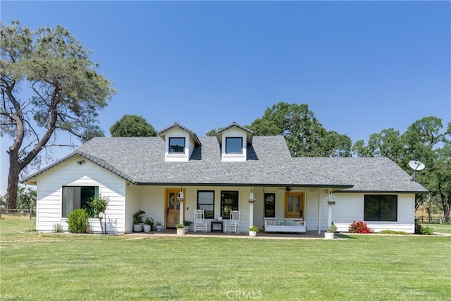 view of front of property with a front lawn, covered porch, roof with shingles, and a ceiling fan