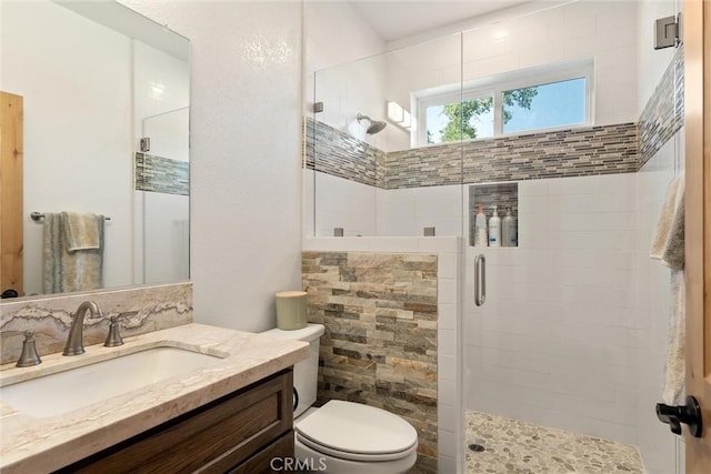 bathroom with a stall shower, vanity, and toilet