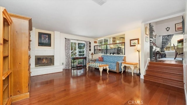 living area with wood finished floors, stairway, and a fireplace