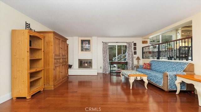 living area with baseboards, wood finished floors, and a fireplace