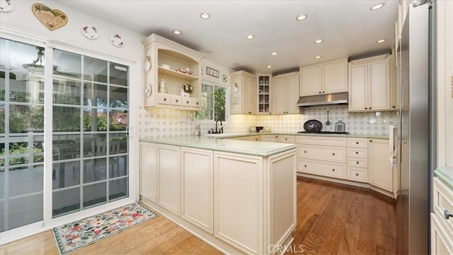 kitchen featuring cream cabinets, a peninsula, and wood finished floors