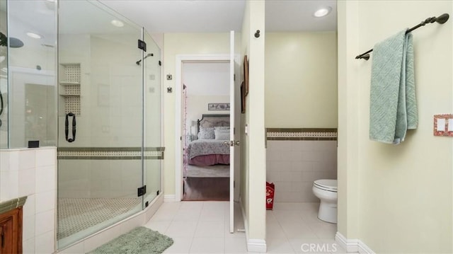ensuite bathroom featuring toilet, tile walls, ensuite bathroom, tile patterned floors, and a stall shower