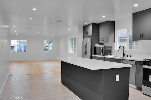 kitchen with a kitchen island, a sink, light countertops, stainless steel appliances, and recessed lighting