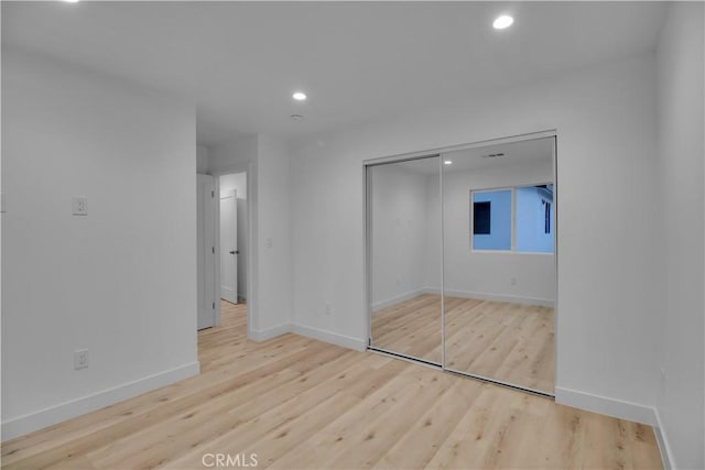 unfurnished bedroom featuring light wood-style floors, recessed lighting, baseboards, and a closet