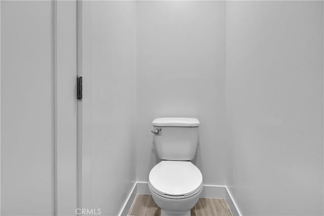 bathroom featuring toilet, baseboards, and wood finished floors