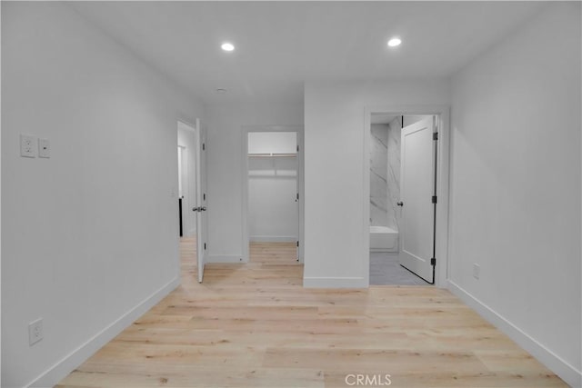 unfurnished bedroom with baseboards, recessed lighting, wood finished floors, and a spacious closet