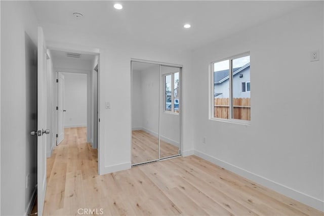 unfurnished bedroom featuring visible vents, a closet, light wood-style floors, baseboards, and recessed lighting