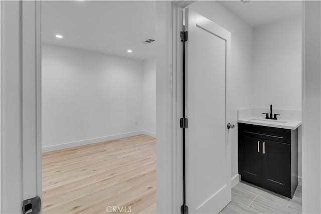 bathroom featuring visible vents, vanity, wood finished floors, baseboards, and recessed lighting