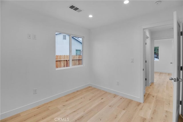 unfurnished room with baseboards, visible vents, a healthy amount of sunlight, and wood finished floors