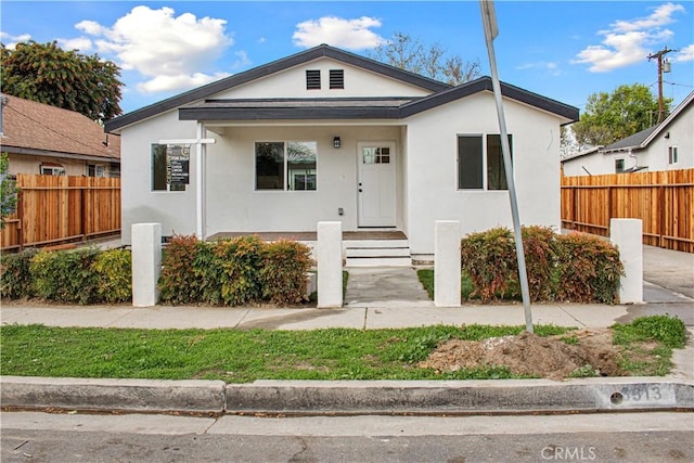 bungalow-style house with fence and stucco siding