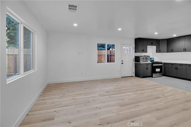 kitchen with visible vents, baseboards, stainless steel gas range, light countertops, and light wood-style flooring