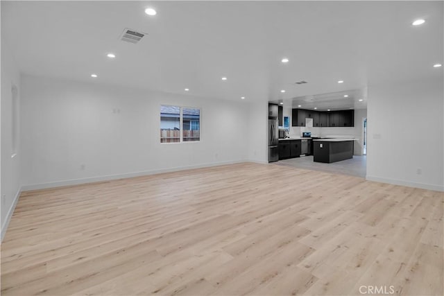 unfurnished living room with recessed lighting, baseboards, light wood-type flooring, and visible vents