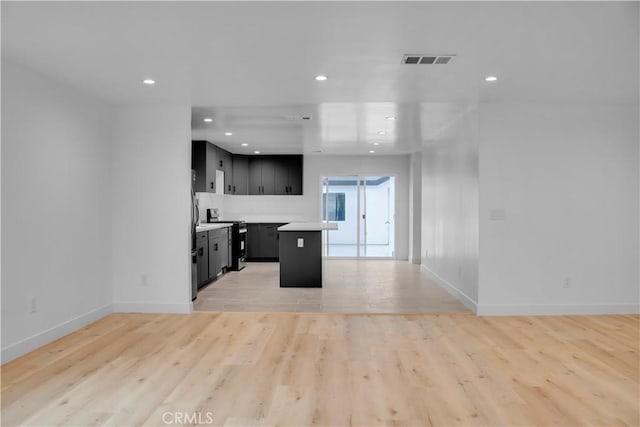 kitchen with light countertops, dark cabinetry, open floor plan, baseboards, and visible vents