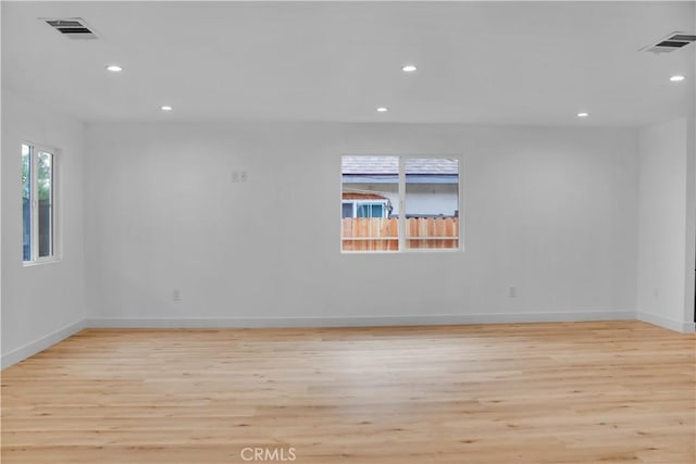 empty room featuring light wood-type flooring, recessed lighting, baseboards, and visible vents