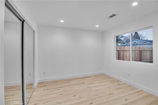 unfurnished bedroom featuring visible vents, baseboards, a closet, light wood-style floors, and recessed lighting