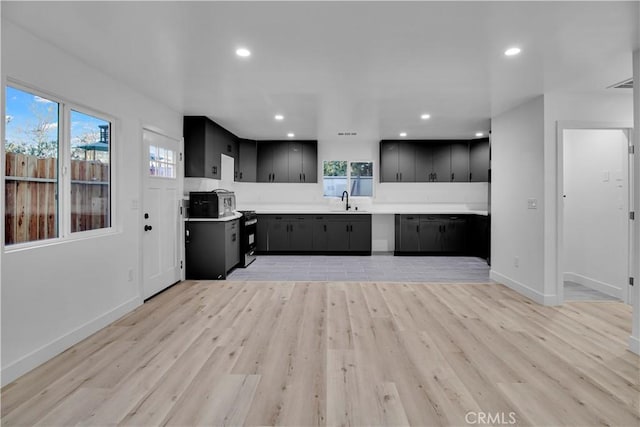 kitchen featuring dark cabinetry, a sink, a healthy amount of sunlight, and light countertops