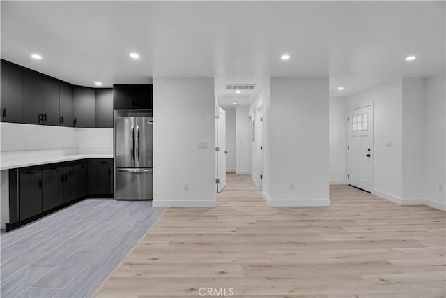 kitchen with dark cabinets, freestanding refrigerator, recessed lighting, and light wood-type flooring