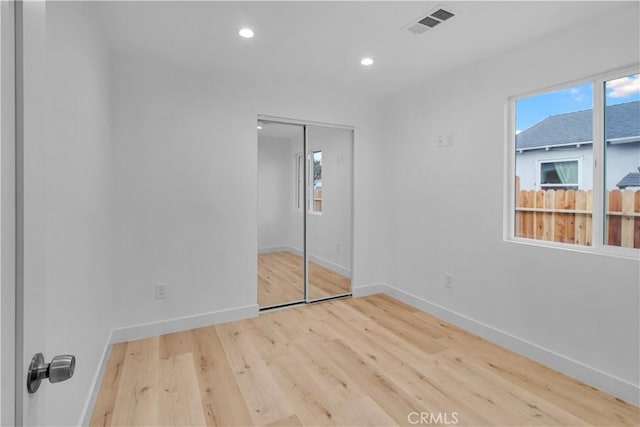 unfurnished bedroom with visible vents, a closet, wood finished floors, baseboards, and recessed lighting