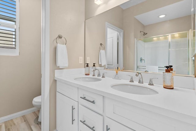 bathroom with double vanity, a sink, toilet, and a shower stall