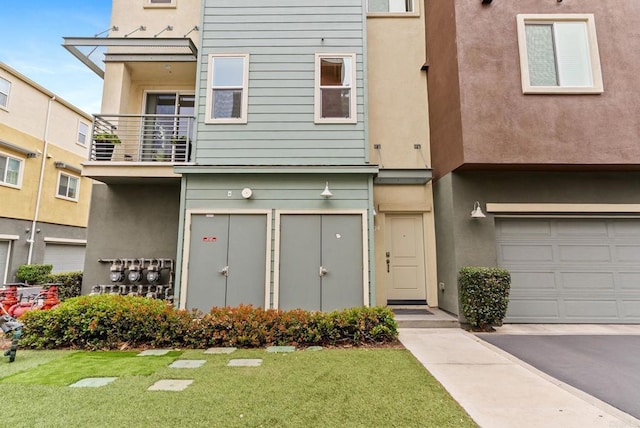 multi unit property with an attached garage, a front lawn, a balcony, and stucco siding