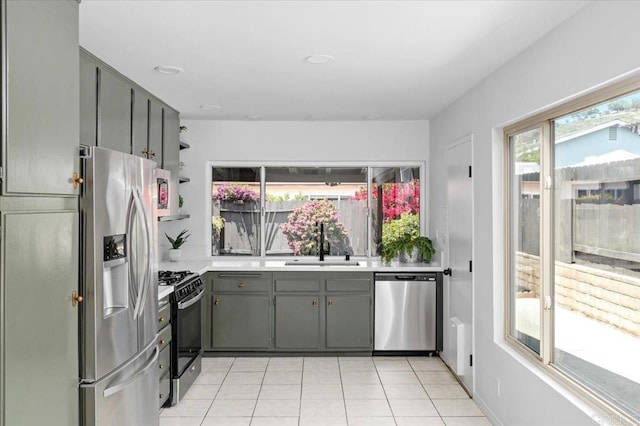 kitchen with gray cabinets, a sink, light tile patterned floors, light countertops, and stainless steel appliances