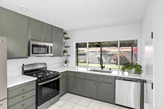 kitchen featuring light tile patterned flooring, open shelves, appliances with stainless steel finishes, a sink, and light countertops