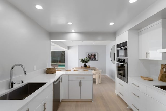 100 Coast Blvd Unit 101, La Jolla, CA 92037 - kitchen featuring a sink, stainless steel appliances, light wood-type flooring, white cabinetry, and a peninsula