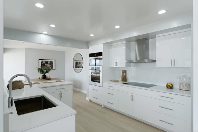 100 Coast Blvd Unit 101, La Jolla, CA 92037 - kitchen with wall chimney exhaust hood, black electric stovetop, a sink, modern cabinets, and light wood-type flooring