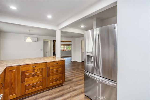 kitchen with recessed lighting, brown cabinetry, wood finished floors, and stainless steel fridge with ice dispenser