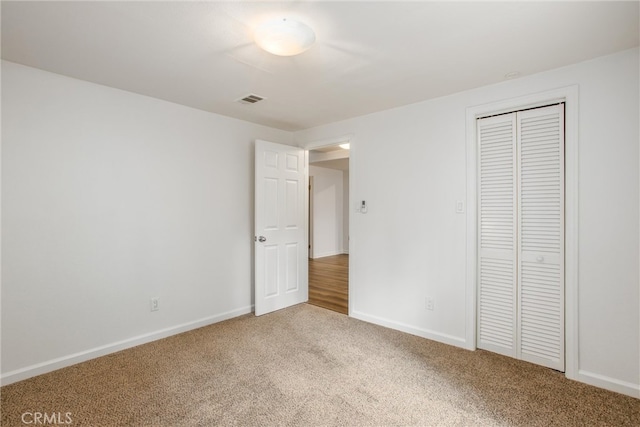 unfurnished bedroom featuring carpet floors, baseboards, visible vents, and a closet