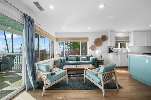 living area featuring recessed lighting, light wood-style flooring, and visible vents