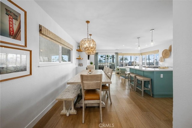 dining space with baseboards, a chandelier, and hardwood / wood-style floors