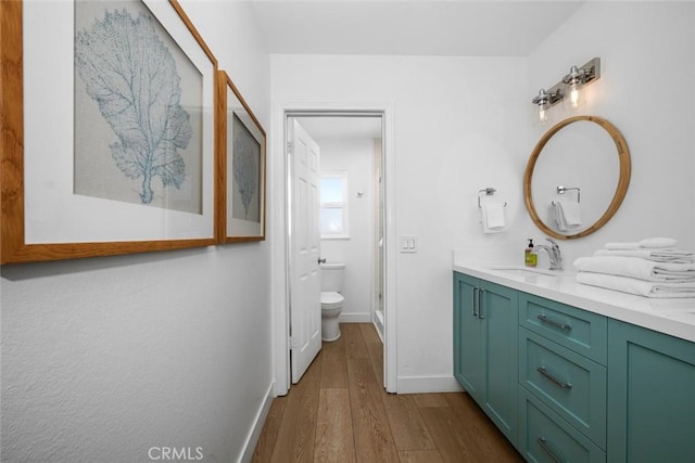 full bath with vanity, wood finished floors, toilet, baseboards, and a stall shower