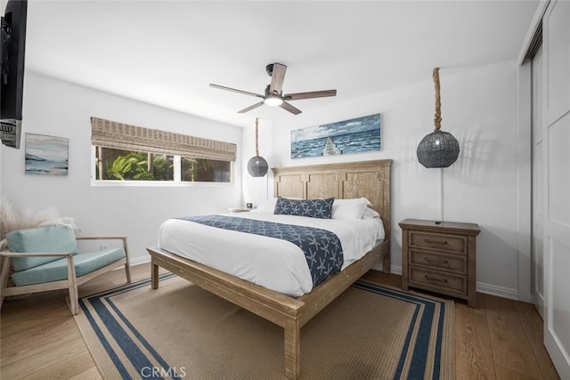 bedroom with a closet, a ceiling fan, light wood-style flooring, and baseboards
