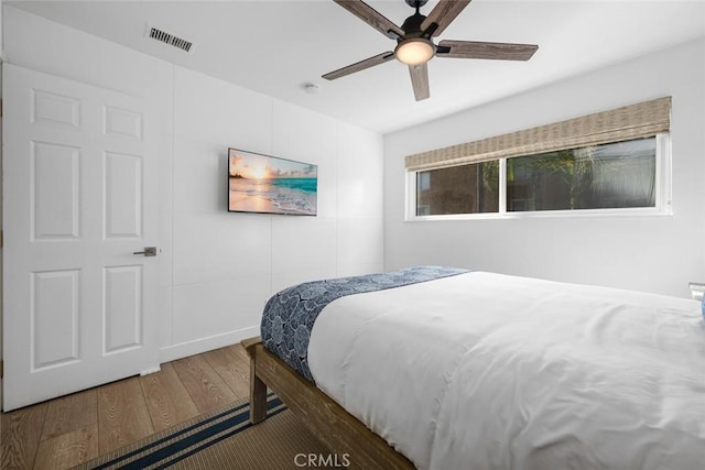 bedroom with ceiling fan, wood finished floors, and visible vents