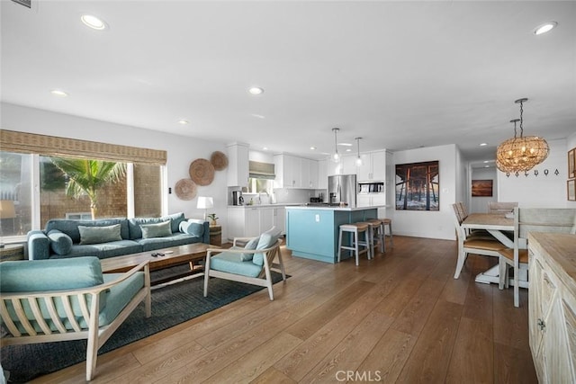 living area with a notable chandelier, a wealth of natural light, and hardwood / wood-style flooring