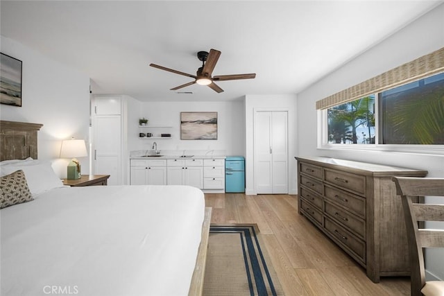 bedroom featuring a sink, ceiling fan, and light wood finished floors