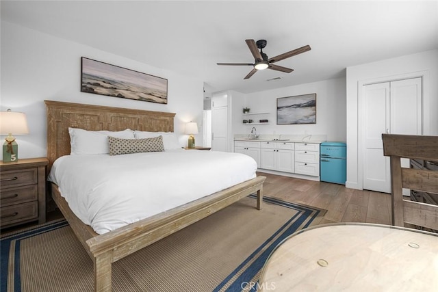 bedroom with a ceiling fan, visible vents, wood finished floors, and a closet