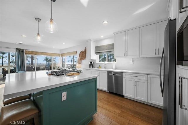 kitchen featuring white cabinets, dark wood-style flooring, light countertops, a breakfast bar area, and stainless steel appliances