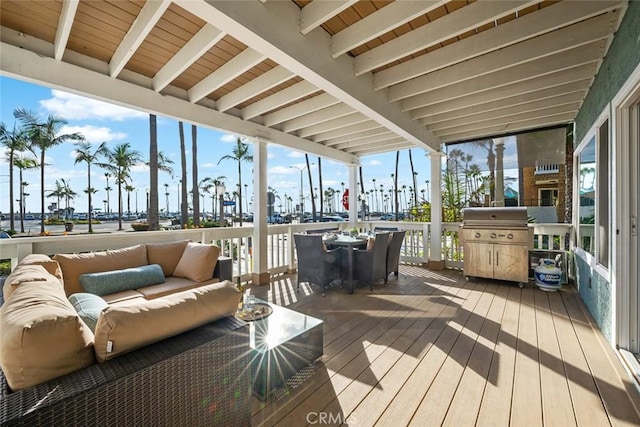 sunroom / solarium featuring hardwood / wood-style floors, a wall of windows, beamed ceiling, a wooden deck, and outdoor lounge area