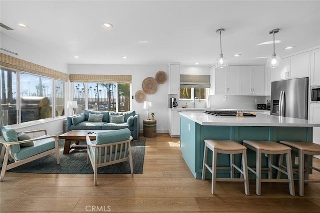 kitchen featuring white cabinets, appliances with stainless steel finishes, a sink, light wood-style flooring, and recessed lighting