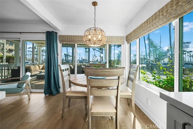 sunroom / solarium with wood-type flooring, baseboards, and a notable chandelier
