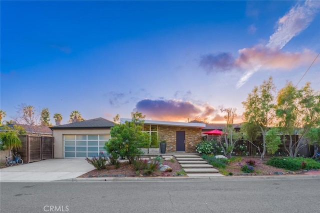 ranch-style house with concrete driveway, an attached garage, fence, and stucco siding