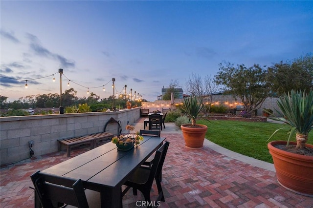 patio terrace at dusk with a lawn and outdoor dining space