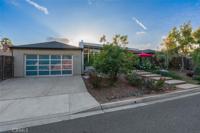 view of front of home with a garage, fence, driveway, and stucco siding